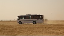 A recreational vehicle driving through the desert.
