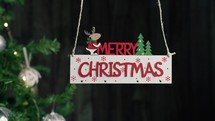 Merry Christmas sign hanging with tree on the background