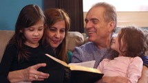 grandparents reading a Bible with their grandkids 