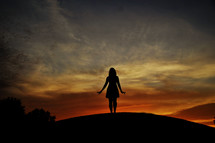 Woman on hill at sunset
