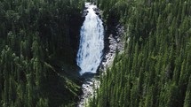 aerial view over a waterfall and green forest 