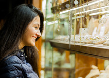 Young woman looking at the showcase of an outdoor jewelry in Florence.