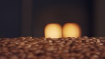 Roasted coffee beans on a conveyor belt with oven fire in the background