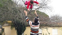 Slow motion of father throwing his daughter in the air.