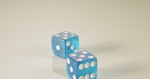 Slow motion macro shot of dice falling and rolling on reflective surface