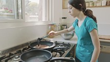 Young kids preparing pancakes in the kitchen using a frying pan