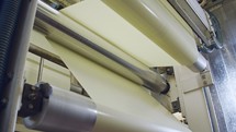 Closeup on paper moving through a large industrial printing machine