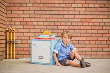 a boy sitting on a locker next to books 