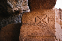 Cross symbol etched in the stone entrance to Lot's cave near the Dead Sea, Jordan.