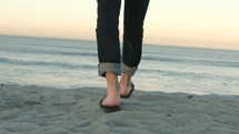 man in flip flops walking on a beach 