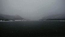 falling winter snow over a lake 
