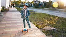 Happy little boy rides children's scooter on city street