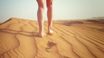 Close-up beautiful female legs in shorts walking on desert sand. Enjoying traveling and relaxing in fresh air in dunes under scorching sun in heat. Summer holidays in another country on vacation.