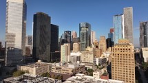 Drone view flying in towards skyscraper buildings in downtown city of Houston, Texas on beautiful blue sky no clouds morning.