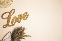 Wooden word love with dried flowers on tan background