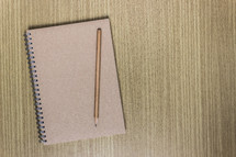 closed notebook and pencil 