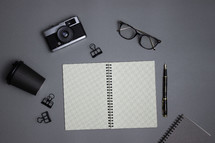 Business notebooks with glasses, camera, cup, and office supplies