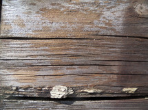 A close-up photograph of weathered and old wood grain showing the age and texture of a piece of wood such as an old wooden cross. 