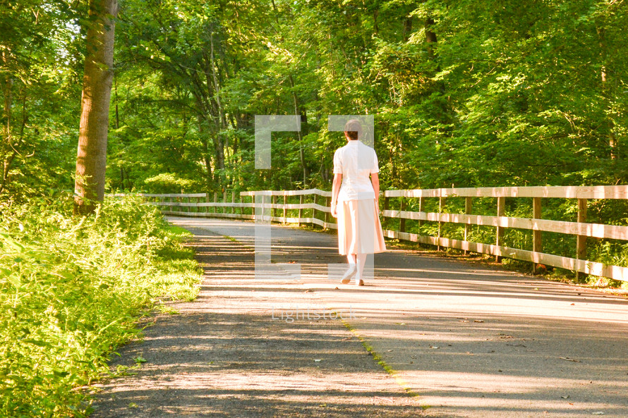 a woman walking on a paved trail 