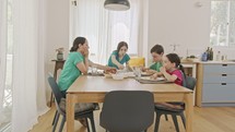 Mother and three kids eating breakfast of pancakes and fruits