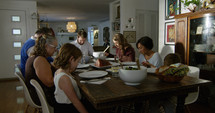 a family saying grace around a dinner table 