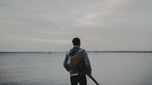 a man holding a guitar near a ashore 