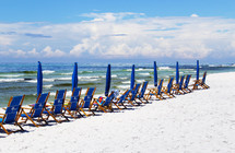 beach chairs and umbrellas on a white sand beach 