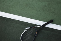Broken tennis racket on the court.