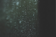 Raindrops shine on a windowpane.
