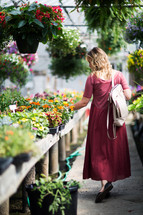 a woman walking through a greenhouse in a garden center 