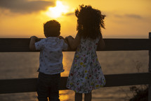 kids looking over a railing at the setting sun 
