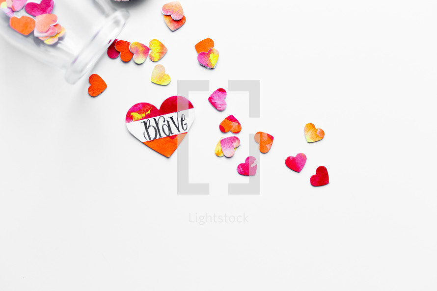 Top view of watercolor hearts scattered on white background with one labeled BRAVE. 