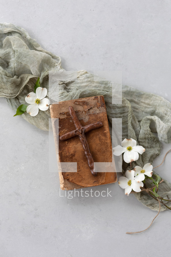 wooden cross and dogwood flowers on an old Bible 