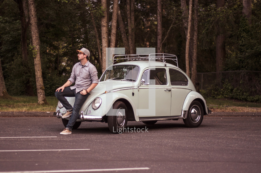 a man sitting on a vintage Volkswagen Beetle 