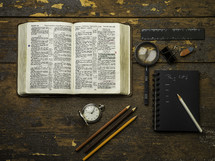 open Bible, pocket watch, pencils, and sketchbook 