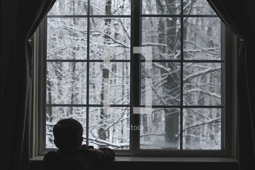 a child watching snow out a window 