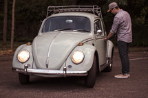 a man opening the door of a vintage Volkswagen Beetle 