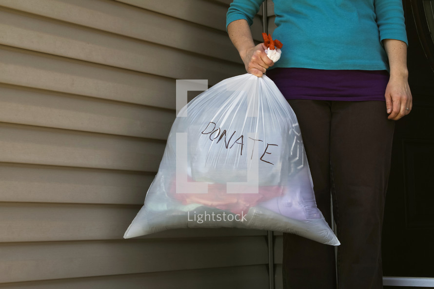 a woman holding a bag of clothes to donate