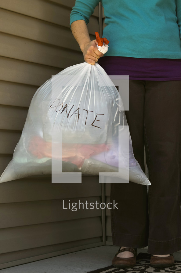 a woman holding a bag of clothes to donate