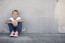 portrait of a child sitting on a sidewalk 
