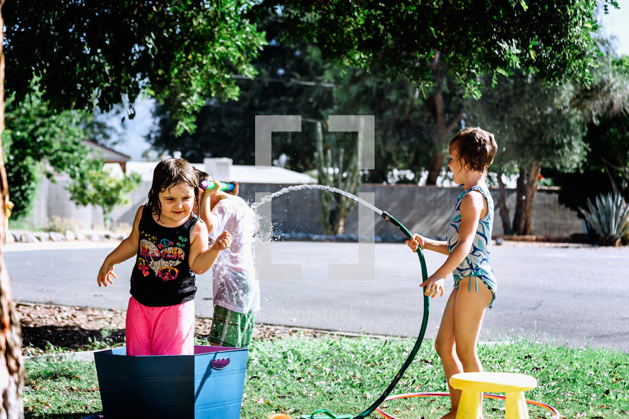 children playing with water outdoors on a hot summer day 