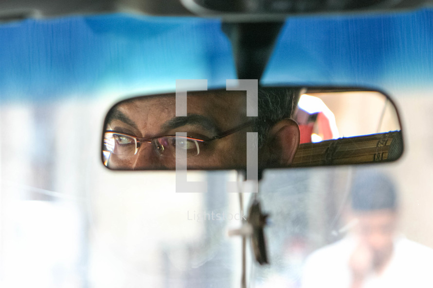 view of a taxi driver in the mirror of a car 