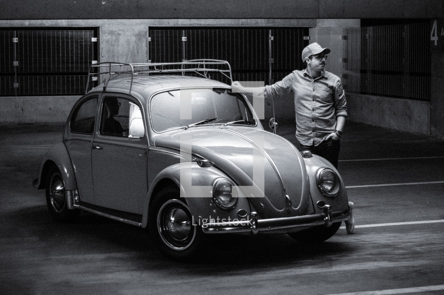 a man leaning against a vintage Volkswagen Beetle 