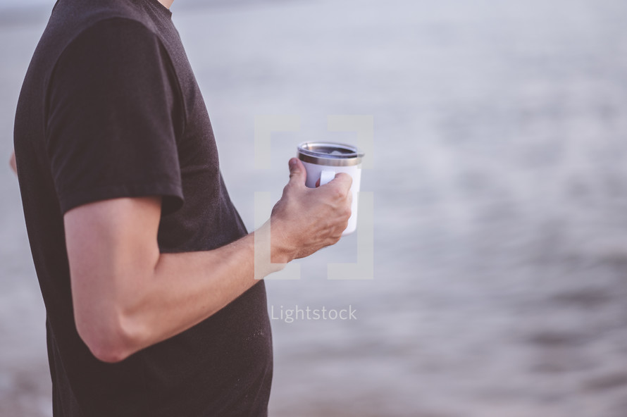 man standing holding a coffee cup 