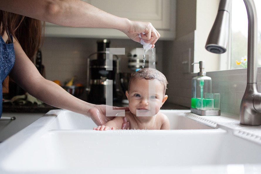 infant getting bathed in a sink 