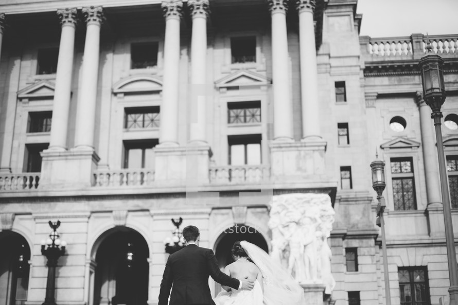a bride and groom walking towards a courthouse 