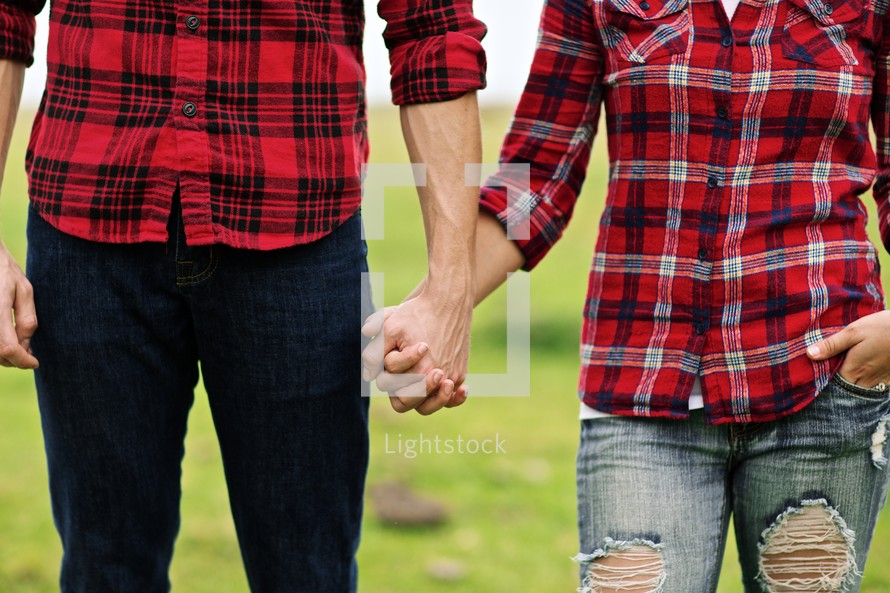 Couple in plais shirts holding hands.
