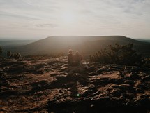 couple sitting on a mountaintop watching a sunset 