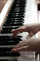 A child's hands playing a piano.