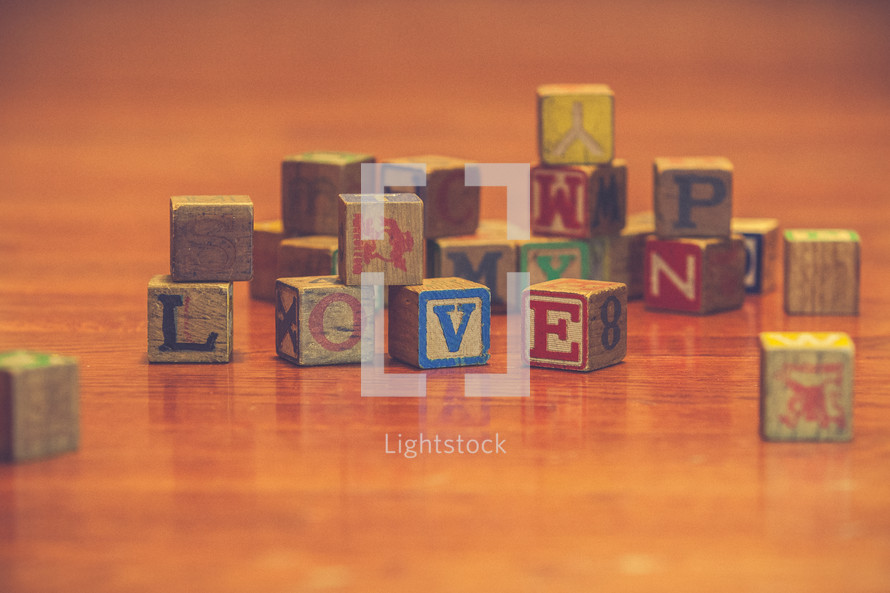 a pile of wood blocks on a playroom floor and the word love 